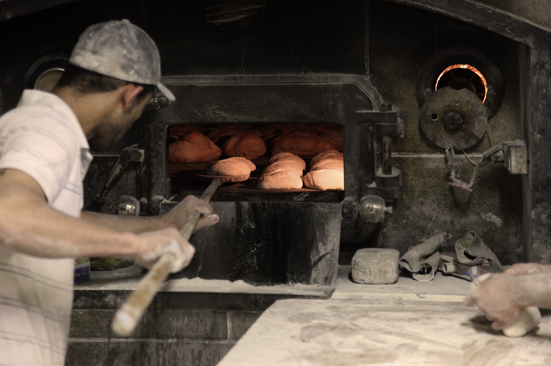 Panadero metiendo bollos al horno