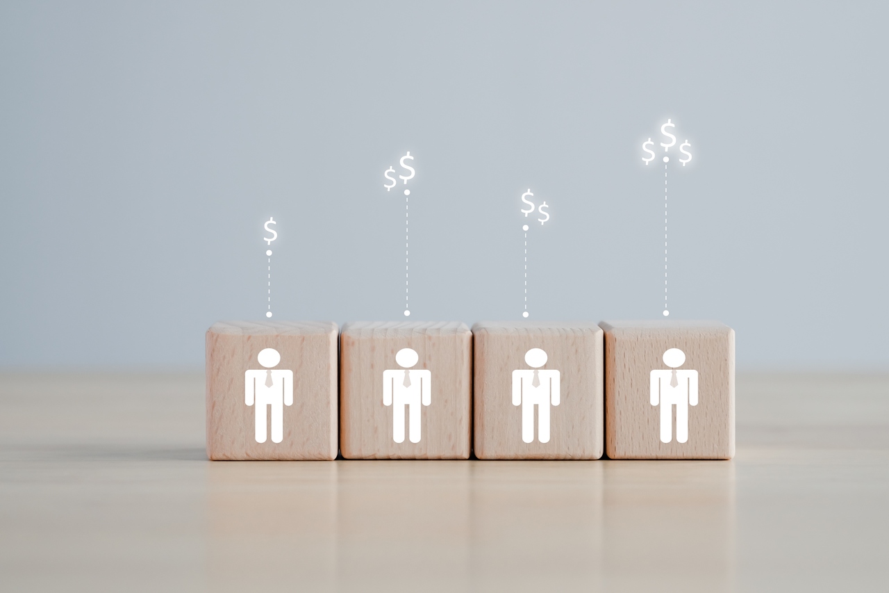 Cuatro cubos de madera ordenados con iconos de personas y signos de pesos iluminados