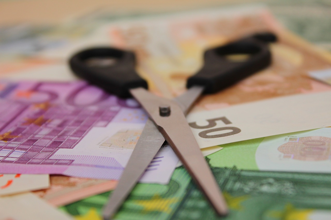 Tijeras encima de billetes de diferentes denominaciones.