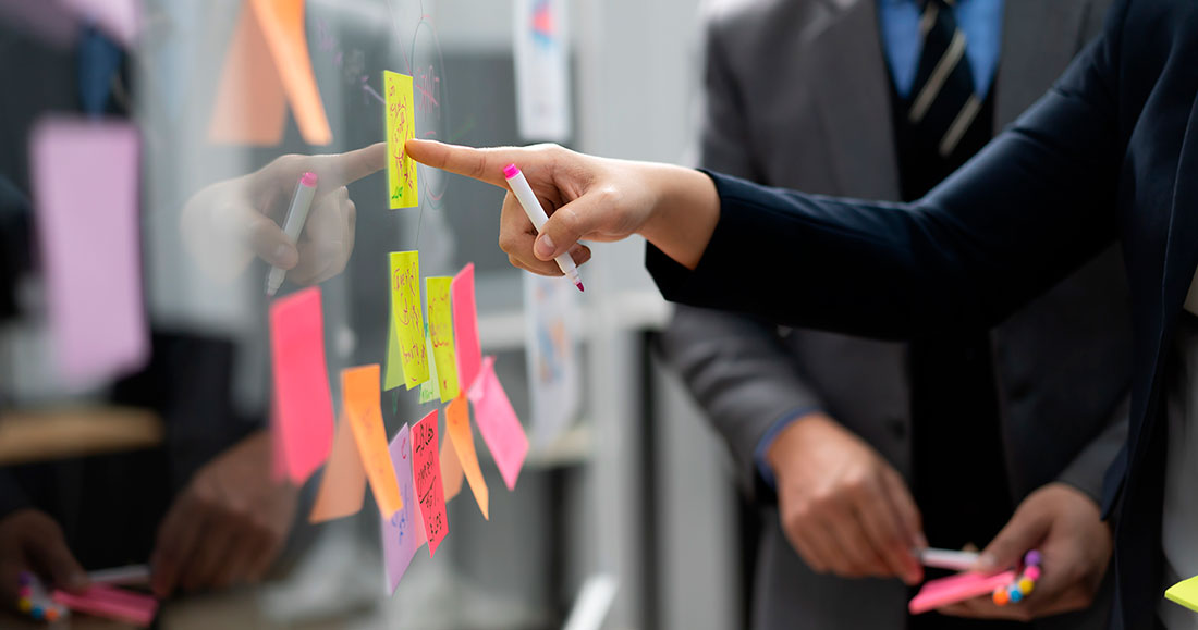Aspectos psicológicos en la toma de decisiones Persona empresaria señalando una nota adhesiva sobre un cristal