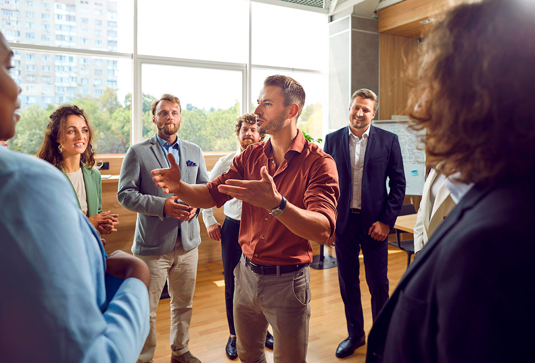 Liderazgo y trabajo en equipo Hombre conversando al centro de un círculo formado con diferentes personas empresarias