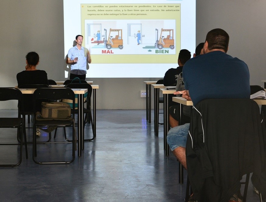 personas sentadas, escuchando la explicación de otra persona.