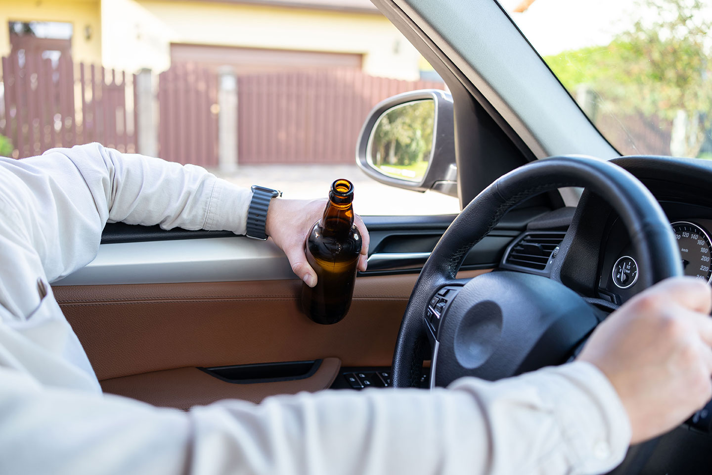 Alcoholismo y desempeño laboral Hombre sosteniendo una botella de alcohol sentado al volante de un automóvil