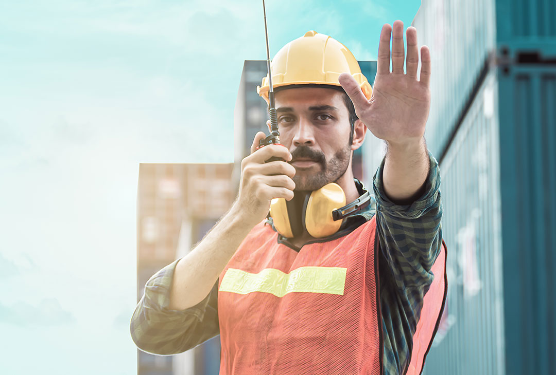 Seguridad laboral Hombre portando elementos de protección sosteniendo radio y casco de seguridad