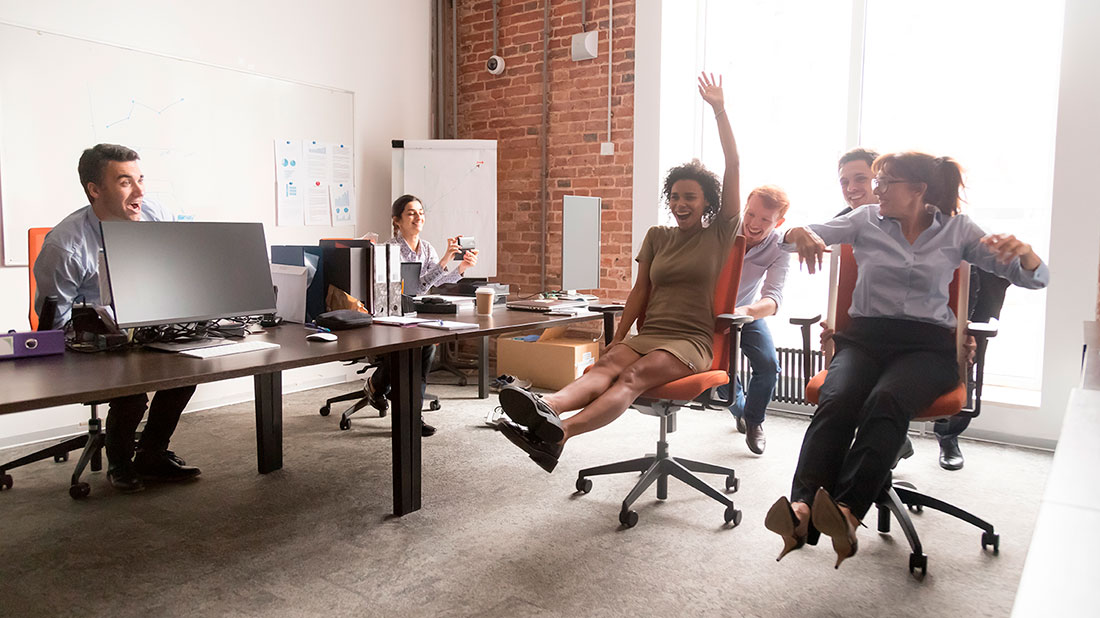 Grupo de personas empresarias sentados en sillas de oficina riendo y estirando los pies