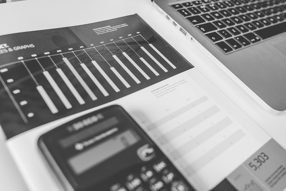 Fotografía de calculadora, computadora y gráficas financieras