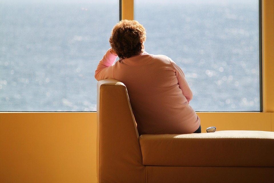  mujer sola sentada viendo a través de una ventana.