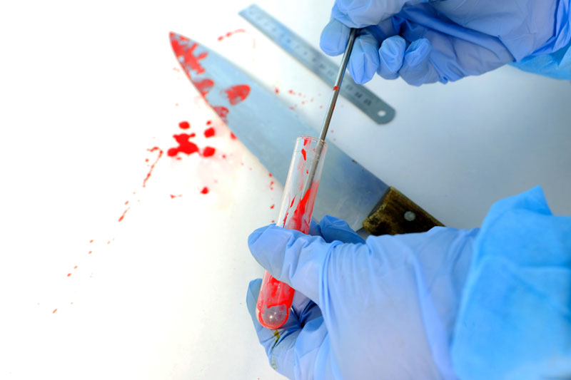 Evidencia de salpicaduras frescas de sangre roja en mesa blanca