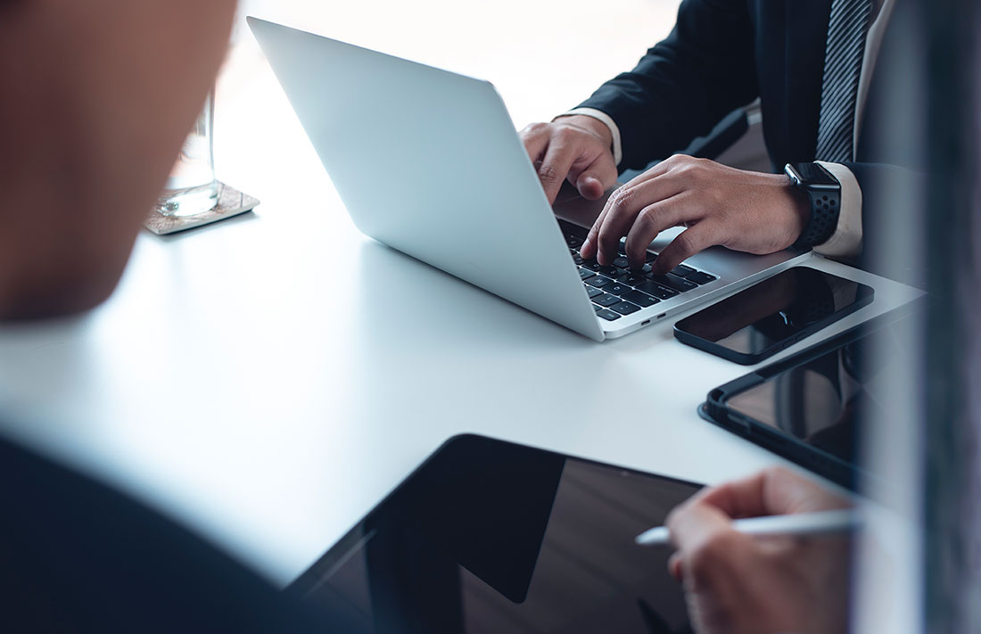 Dos personas empresarias trabajando con una laptop, una tableta y un teléfono celular