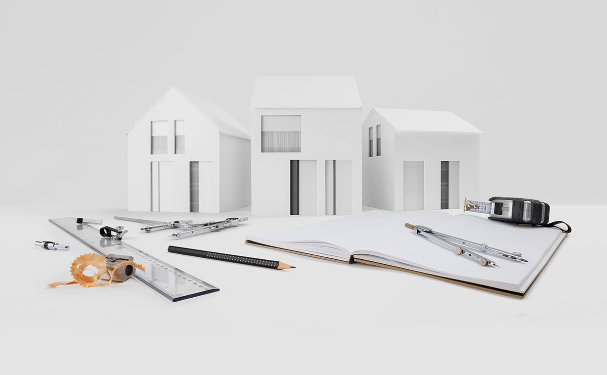 Modelo arquitectónico de casas sobre un escritorio con herramientas técnicas de dibujo
