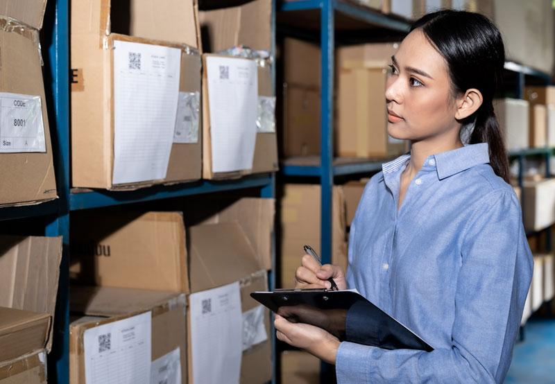 Mujer clasificando archivos en un estante. La organización asegura la disponibilidad, localización, integridad y conservación de los documentos