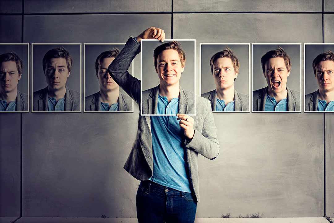 Hombre sosteniendo foto de su rostro a lado de fotos con diferentes rostros