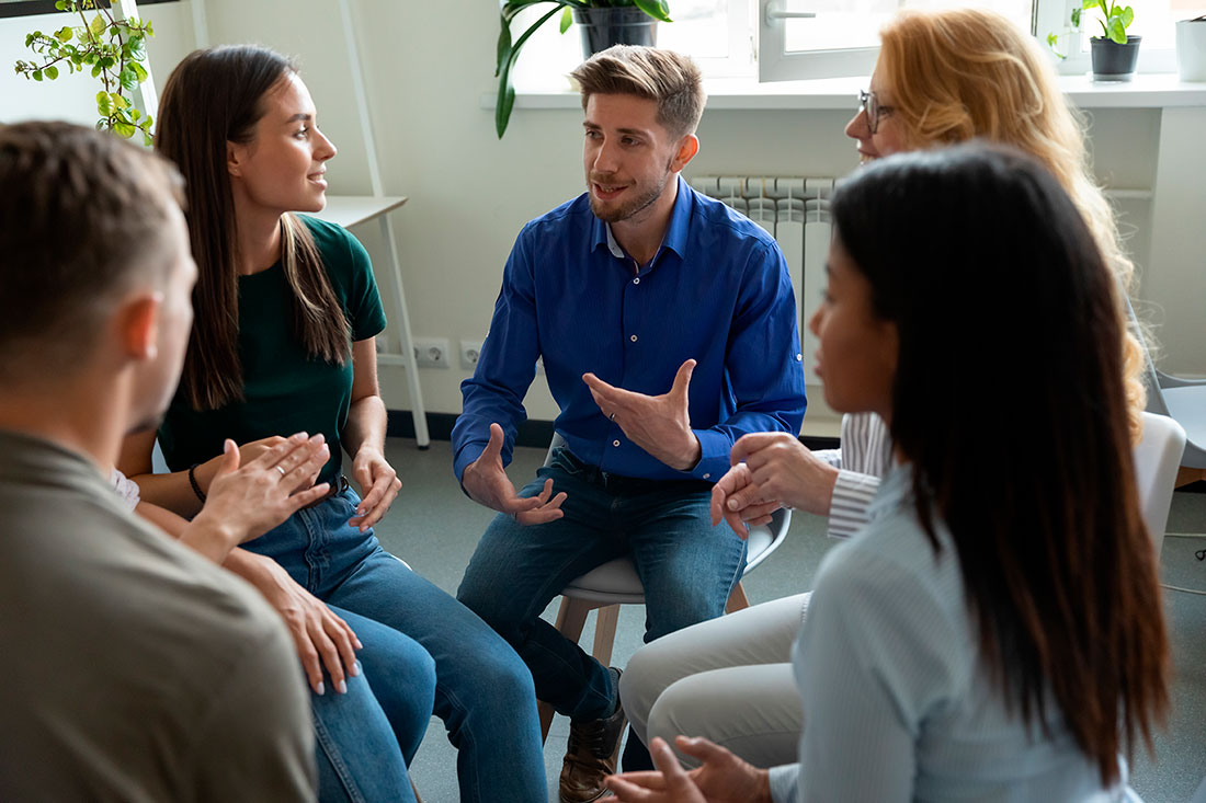Grupo de personas reunidas en círculo en una oficina conversando y sonriendo