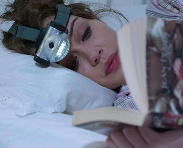 Mujer con lámpara en la frente leyendo libro