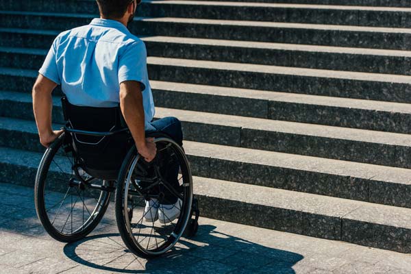 Importancia de la accesibilidad Hombre en silla de ruedas frente a escalera