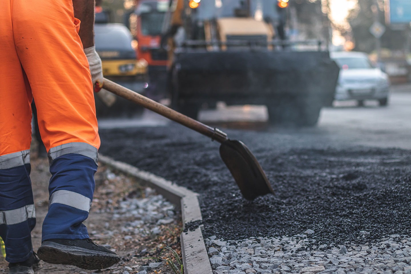 Un trabajador colocando pavimento de asfalto para reparar una carretera 