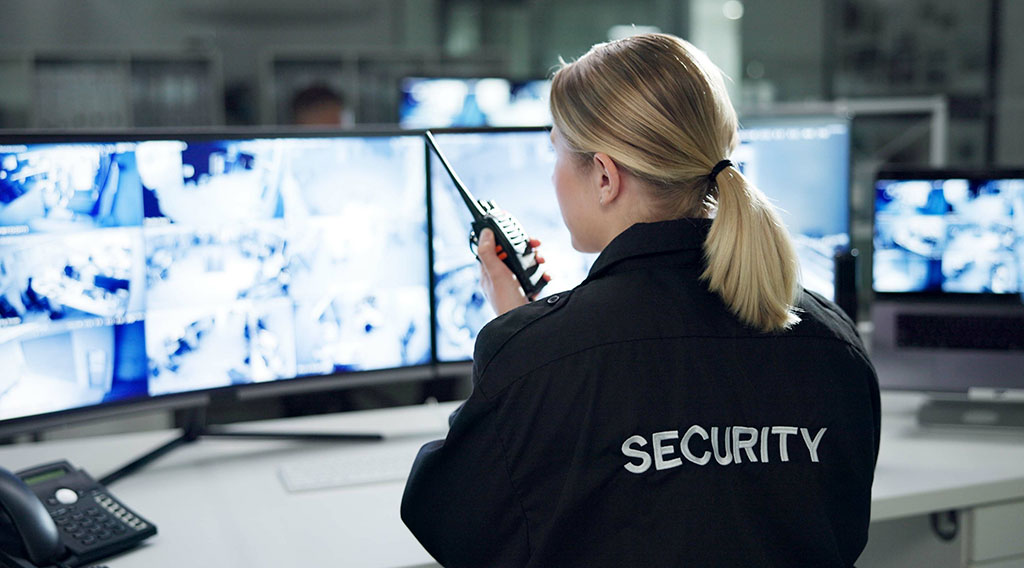Guardia de seguridad monitoreando cámaras de vigilancia en la sala de control Guardia de seguridad revisa monitores de vigilancia en una sala de control