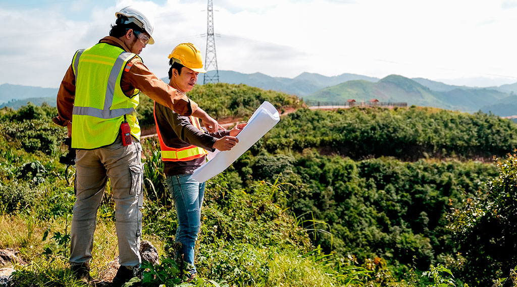 Ingenieros en una inspección de campo Ingenieros revisan planos de construcción en una montaña