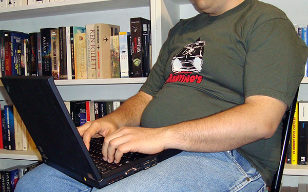 Hombre sentado con una computadora en las piernas.