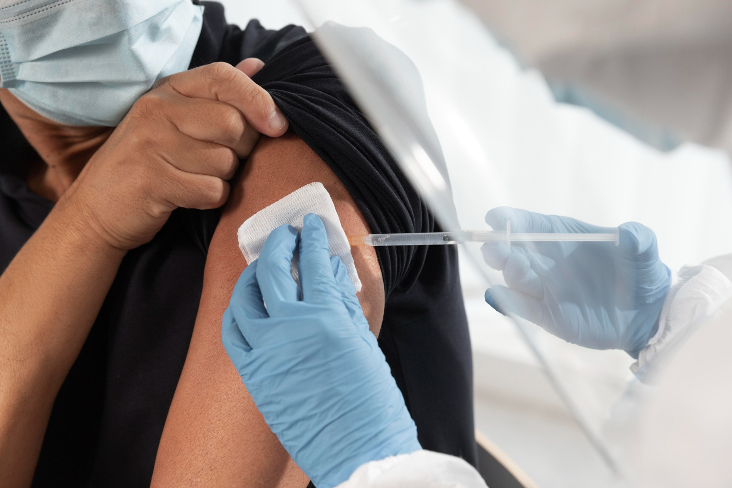 Doctor inyectando en el brazo a un hombre.