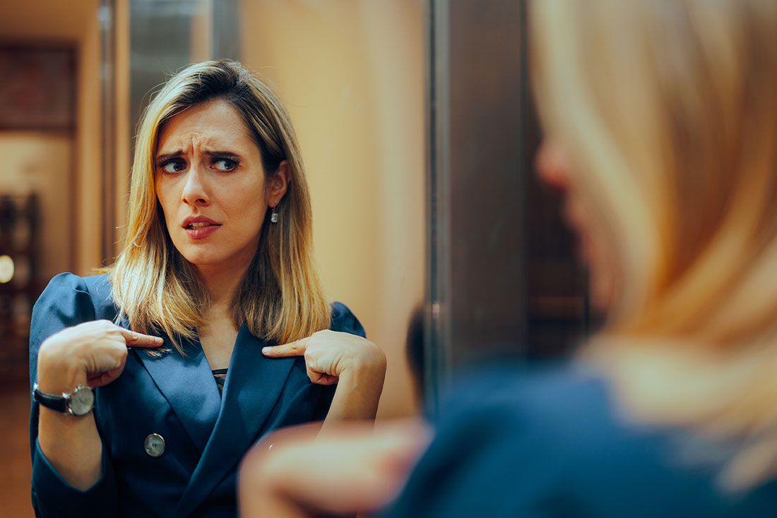 Mujer mirándose al espejo, señalándose y analizándose