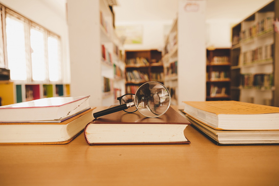 Lupa sobre libro dentro de una biblioteca